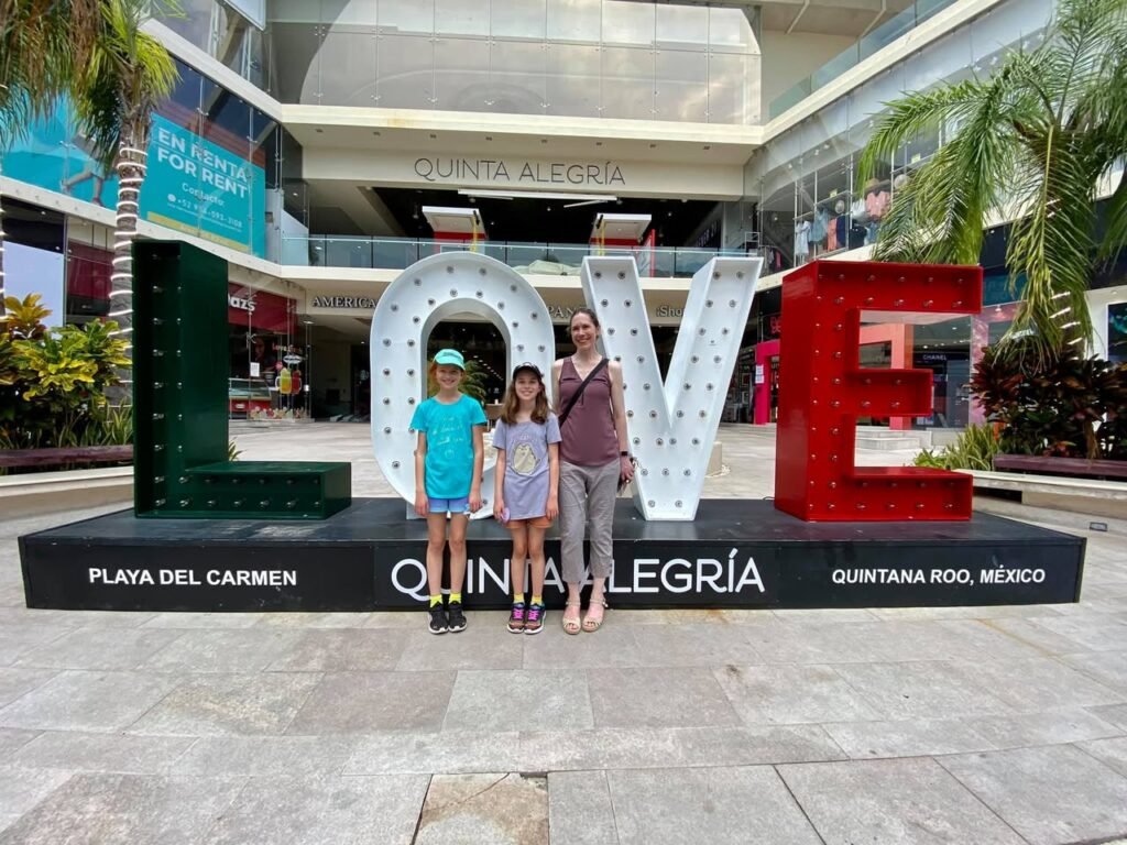 Two children and one adult stand in front of the Love Sign at Quinta Alegria in Playa del Carmen, Mexico.