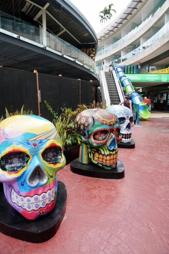 Vibrant, hand-painted sugar skull sculptures on display in a modern outdoor plaza in Chula Vista, California.