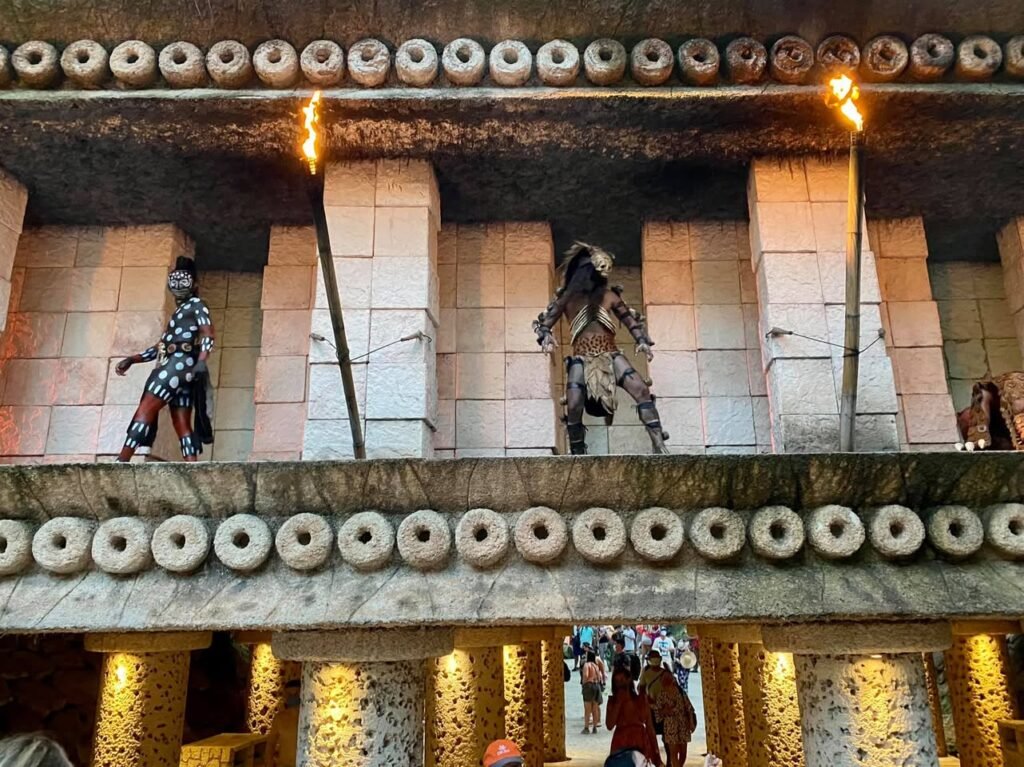 Traditional dancers holding burning torches perform on an elevated balcony of an Oba of Benin palace.