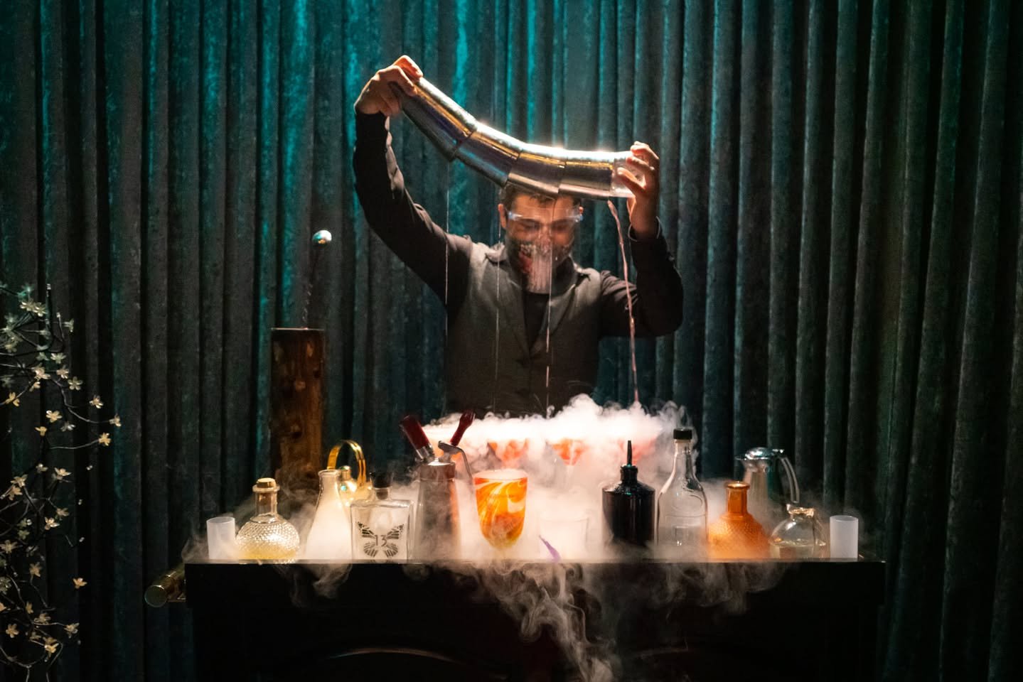 Cirque du Soleil: JOYÀ A bartender performs a theatrical cocktail demonstration using dry ice smoke and a curved glass tube.