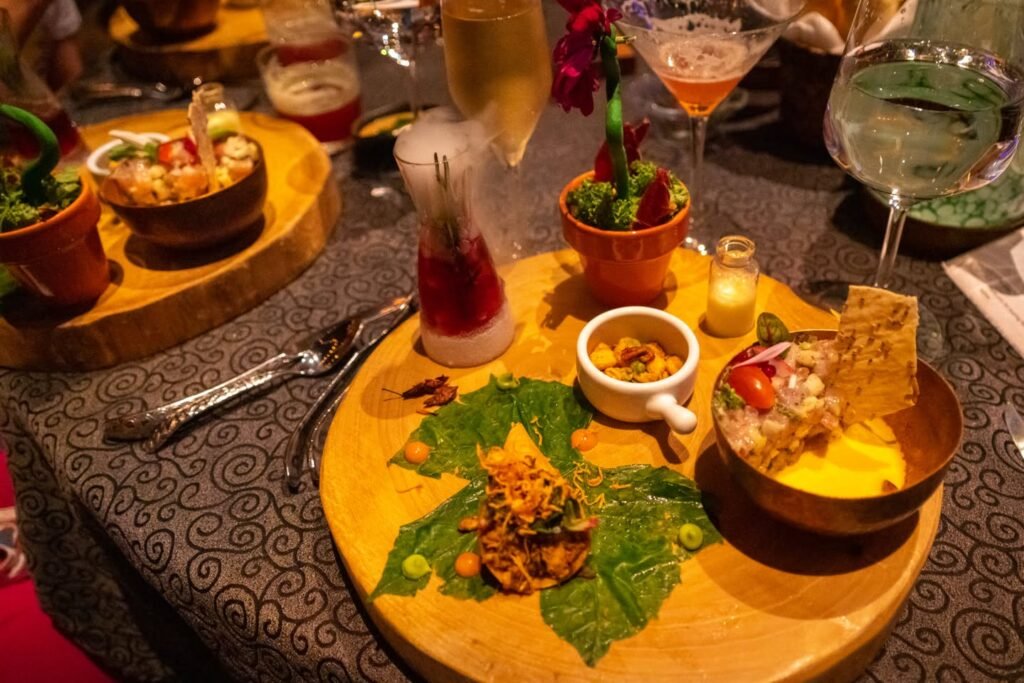 Close-up of appetizers in small bowls with decorative leaves and martinis on a patterned tablecloth.