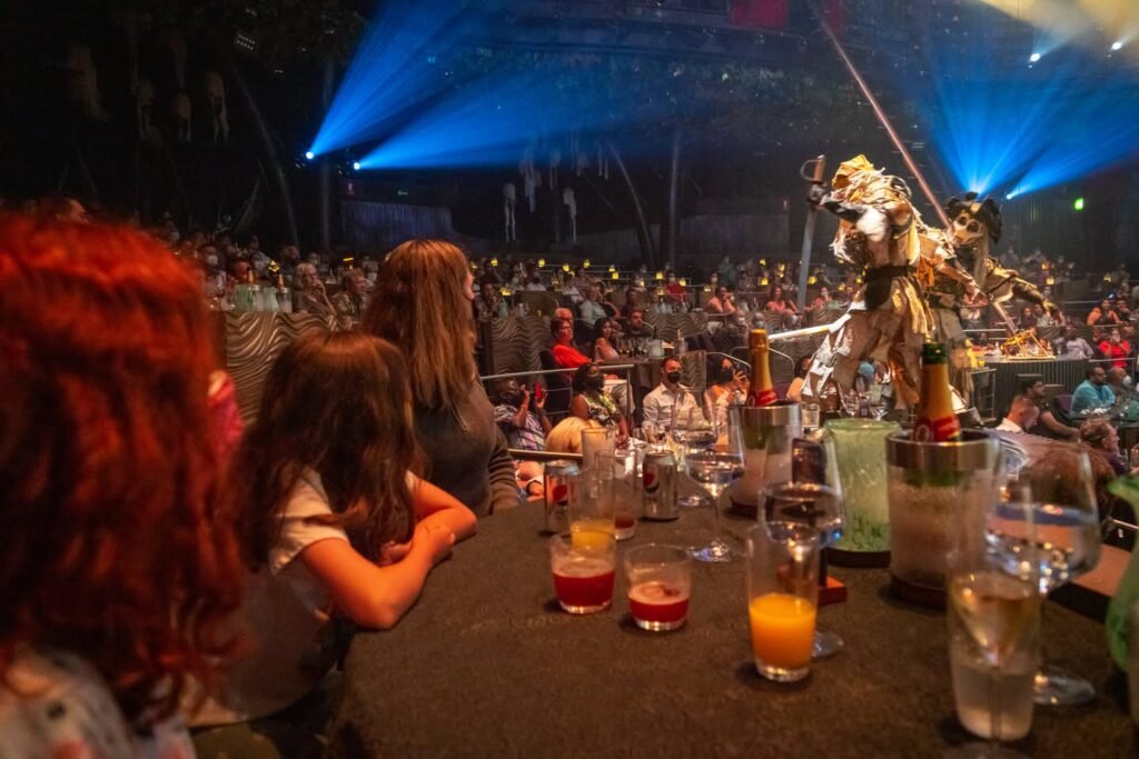 A composite image showing a lively concert scene with people at a table with drinks and stage lights.