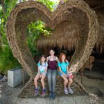 Tulum Vacation Home A family poses for a photo inside a large heart-shaped sculpture made of woven natural fibers.