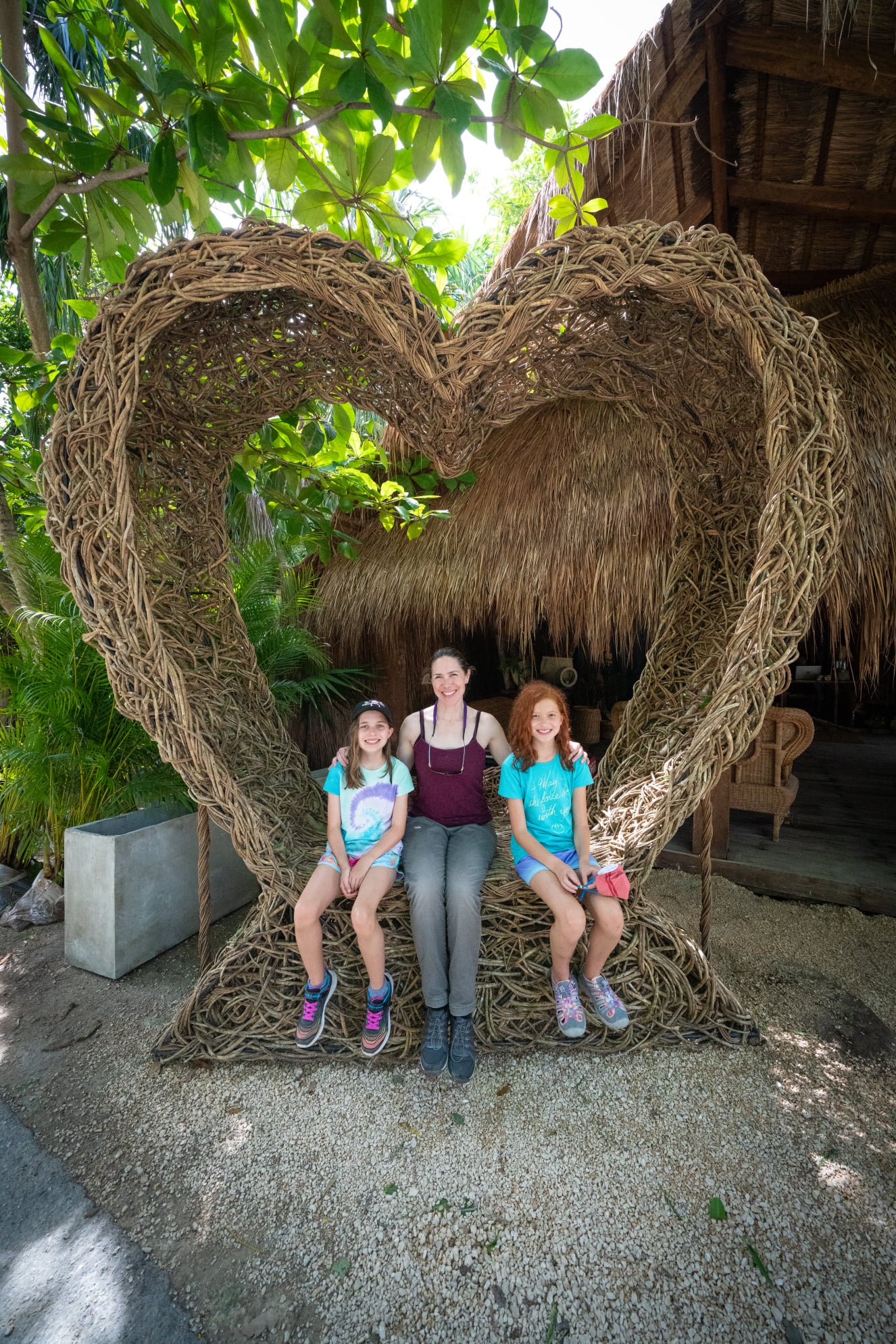 Tulum A family poses for a photo inside a large heart-shaped sculpture made of woven natural fibers.