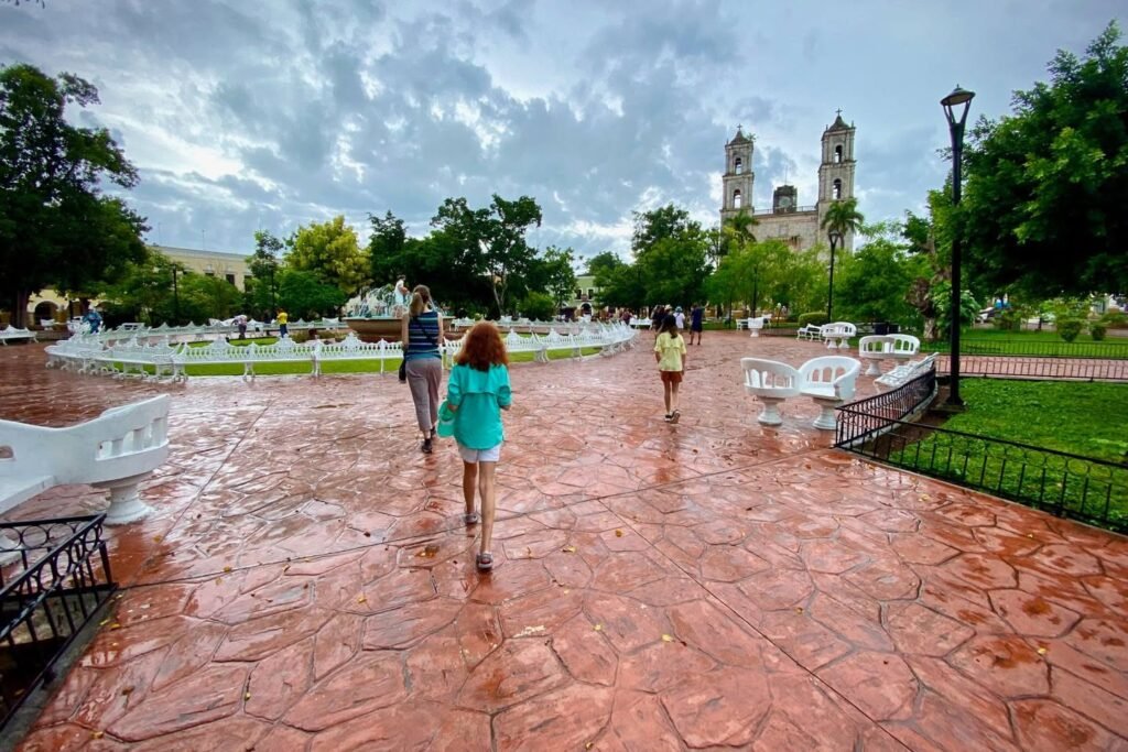 Two people walking on a red-brick plaza towards a cathedral.