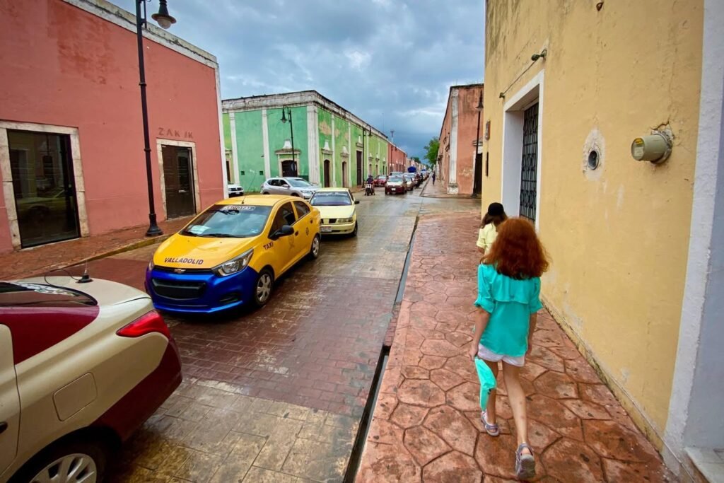 Vibrant narrow city street lined with colorful buildings including pink, green, and yellow structures.