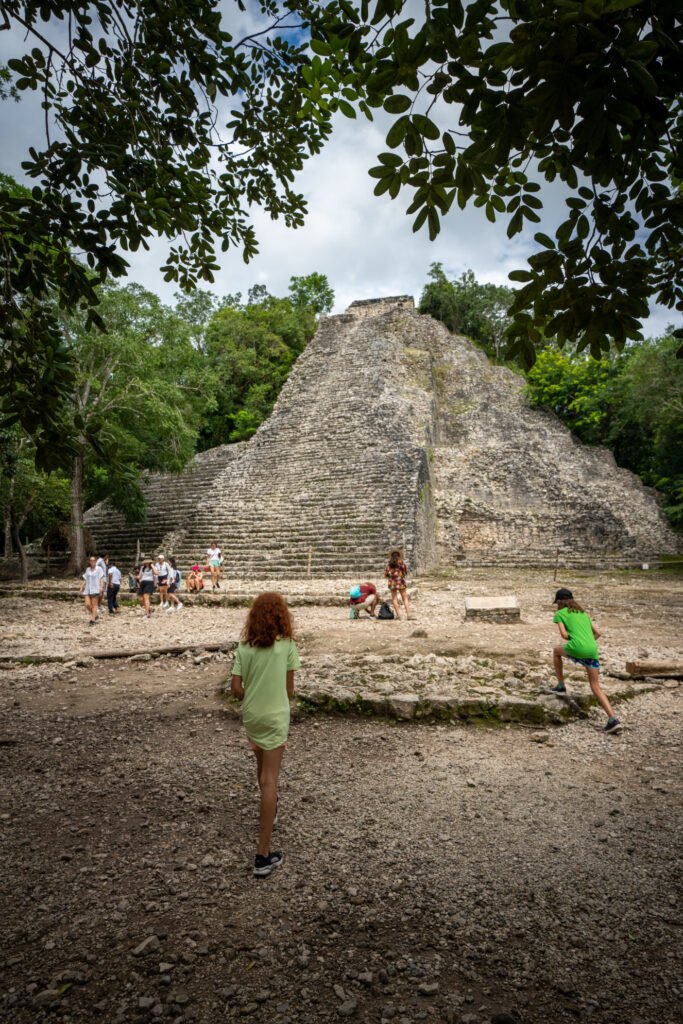 A large stone pyramid rises from the jungle with children playing in the foreground.