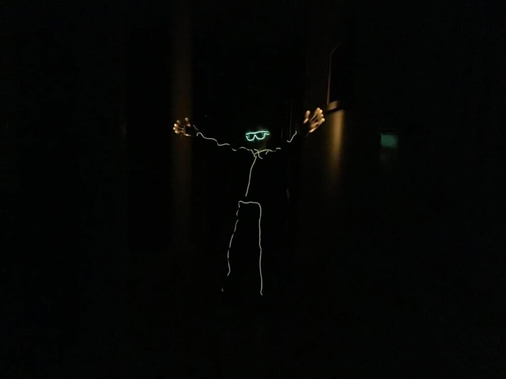 A glowing figure and glasses against a dark background, capturing the essence of long-exposure photography in low light.