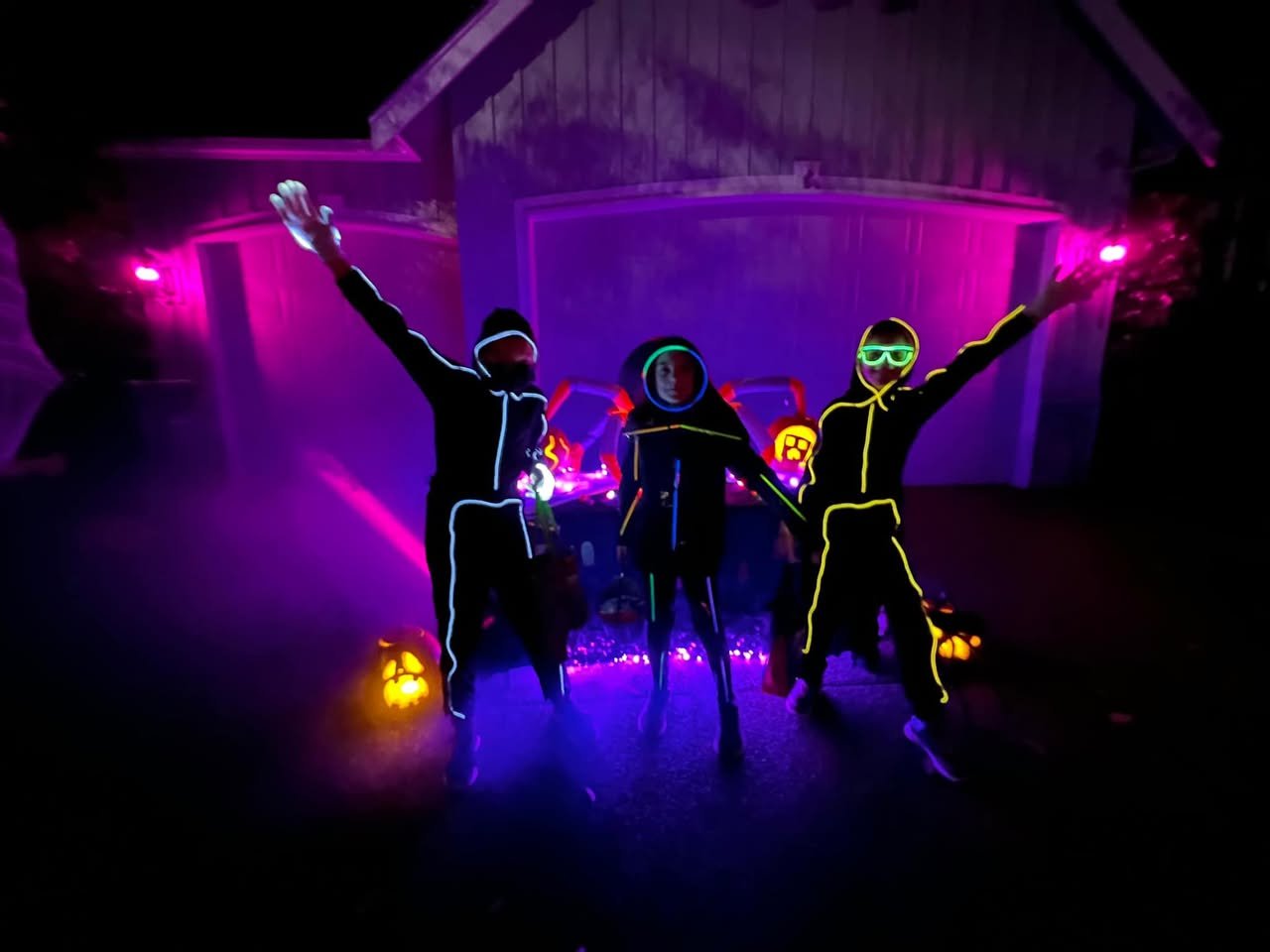 Happy Halloween Floating pumpkin-shaped drones with lit interiors glowing in purple light. People with neon face paint dance among floating pumpkin lights.