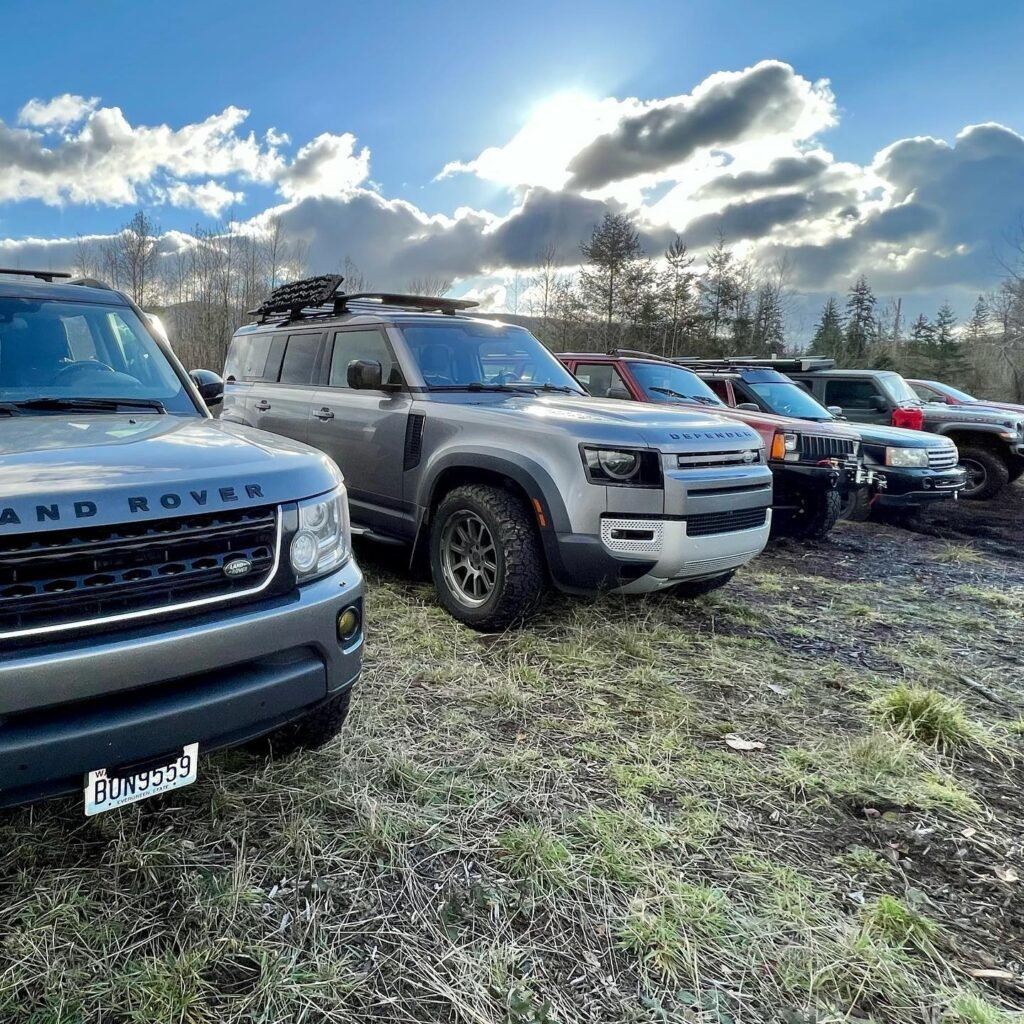 A lineup of off-roaders parked on a grassy field beneath a dynamic sky.