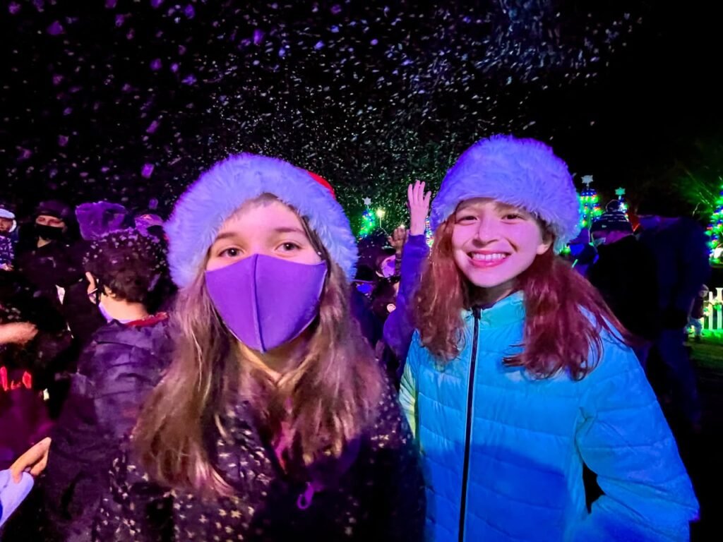 Two people bundled up in warm hats and jackets enjoy a night of festive lights.