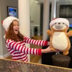 Suncadia Christmas 2021 A joyful moment with a child in festive pajamas holding a matching plush bear at home.
