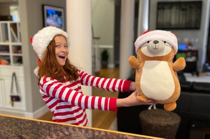 A joyful moment with a child in festive pajamas holding a matching plush bear at home.