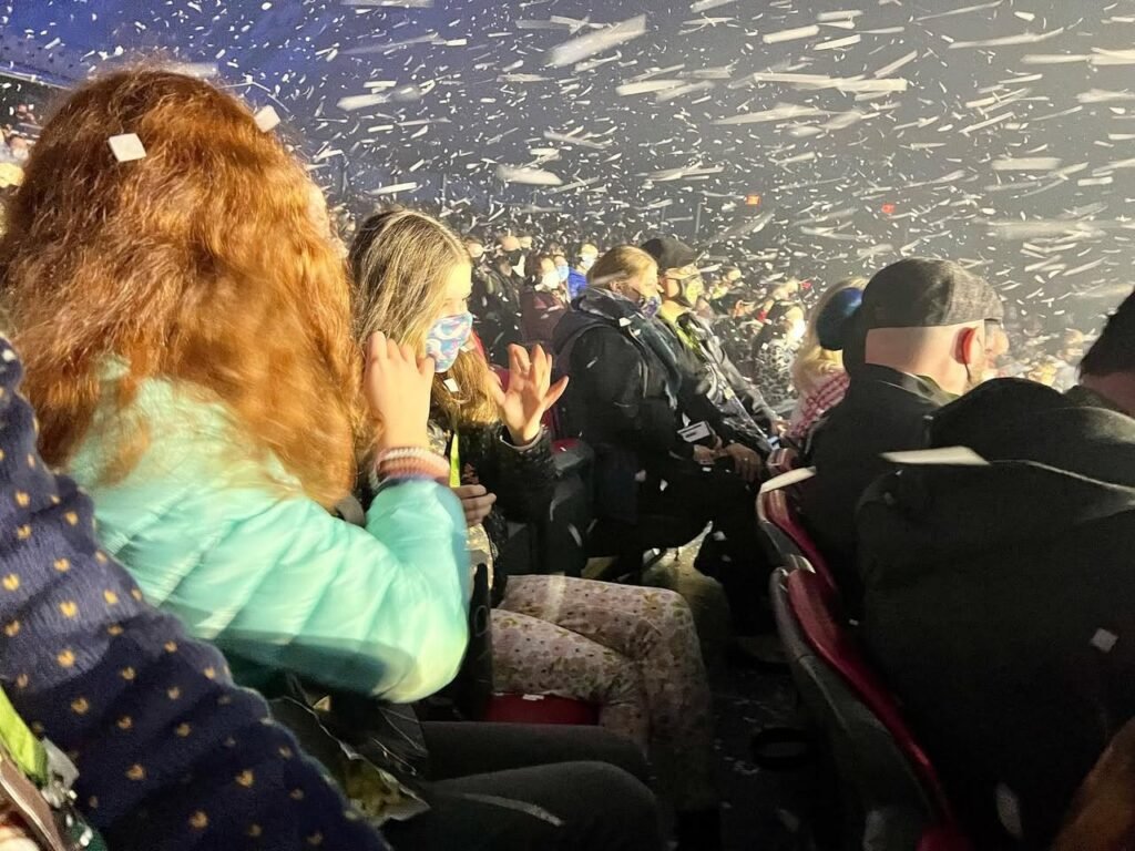 A spectator watches confetti fall from the sky at a lively event.