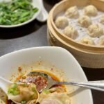 A steaming basket of tian bao alongside soup dumplings in red broth, typical of an authentic Chinese dim sum meal.