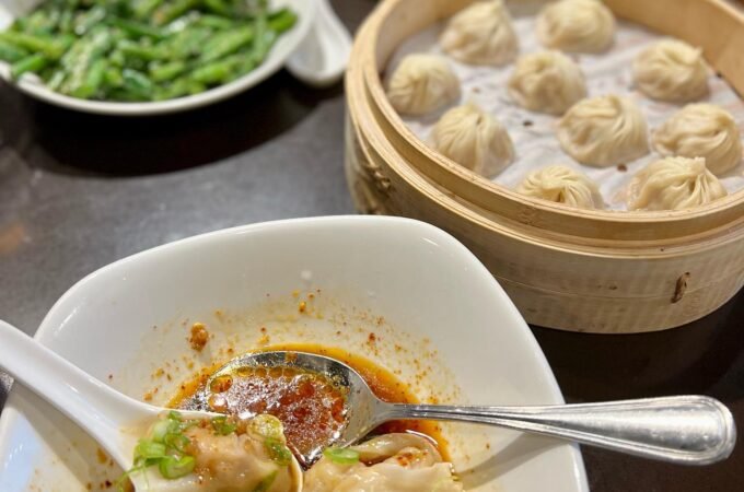 A steaming basket of tian bao alongside soup dumplings in red broth, typical of an authentic Chinese dim sum meal.
