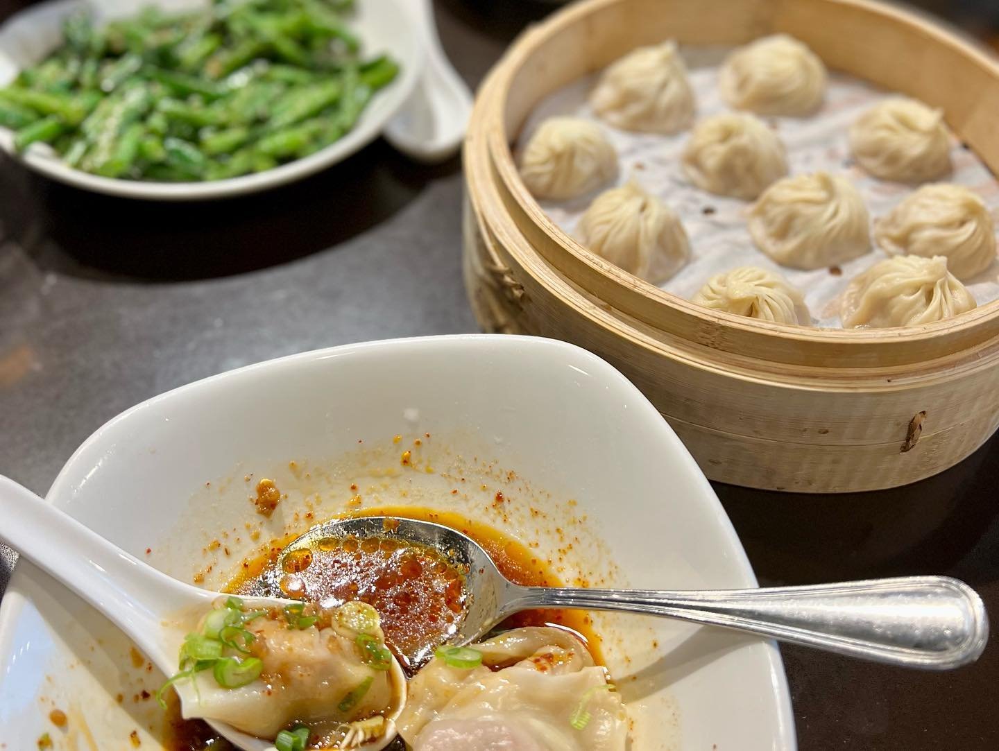 Valentine’s Date Night A steaming basket of tian bao alongside soup dumplings in red broth, typical of an authentic Chinese dim sum meal.