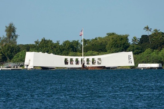 A white ship-shaped monument displays 'BIKINI' with an American flag flying against a tropical tree-lined shore. Another view shows the Pacific waters in front of the memorial.