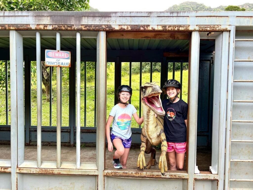 Happy kids wearing safety helmets visit an open-air reptile enclosure at a Pacific Northwest nature park.