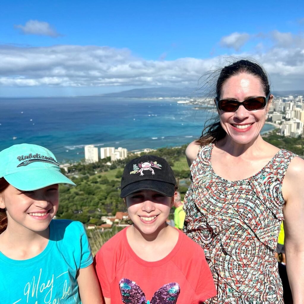 Family smiling in front of a beautiful ocean view with coastal city in the background.