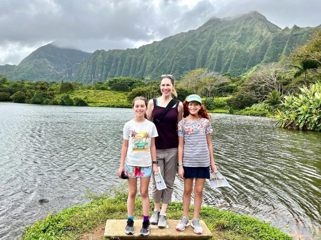 Three visitors enjoy a scenic view of Olowalu Pond in Maui, featuring the distinctive Ko'olau range in the background.