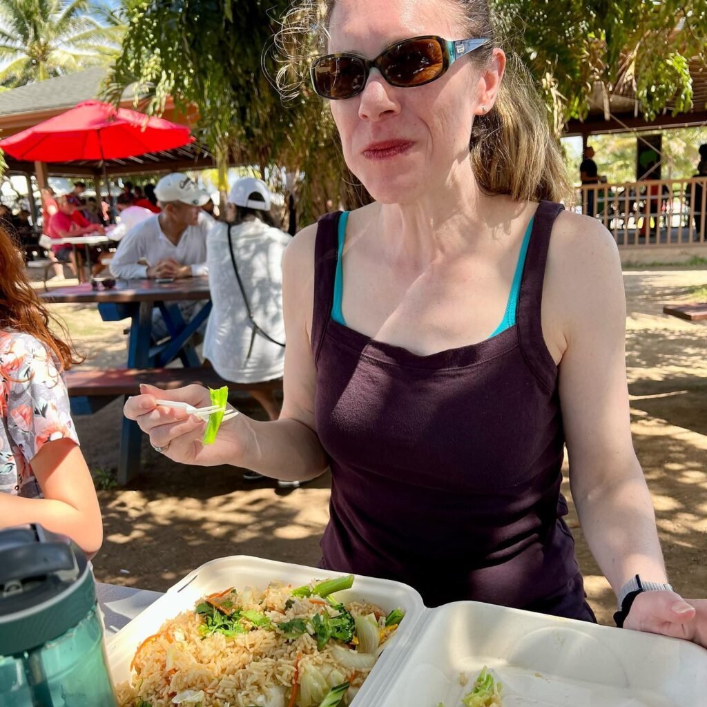 Enjoying a tropical lunch with a plate of food under palm trees.