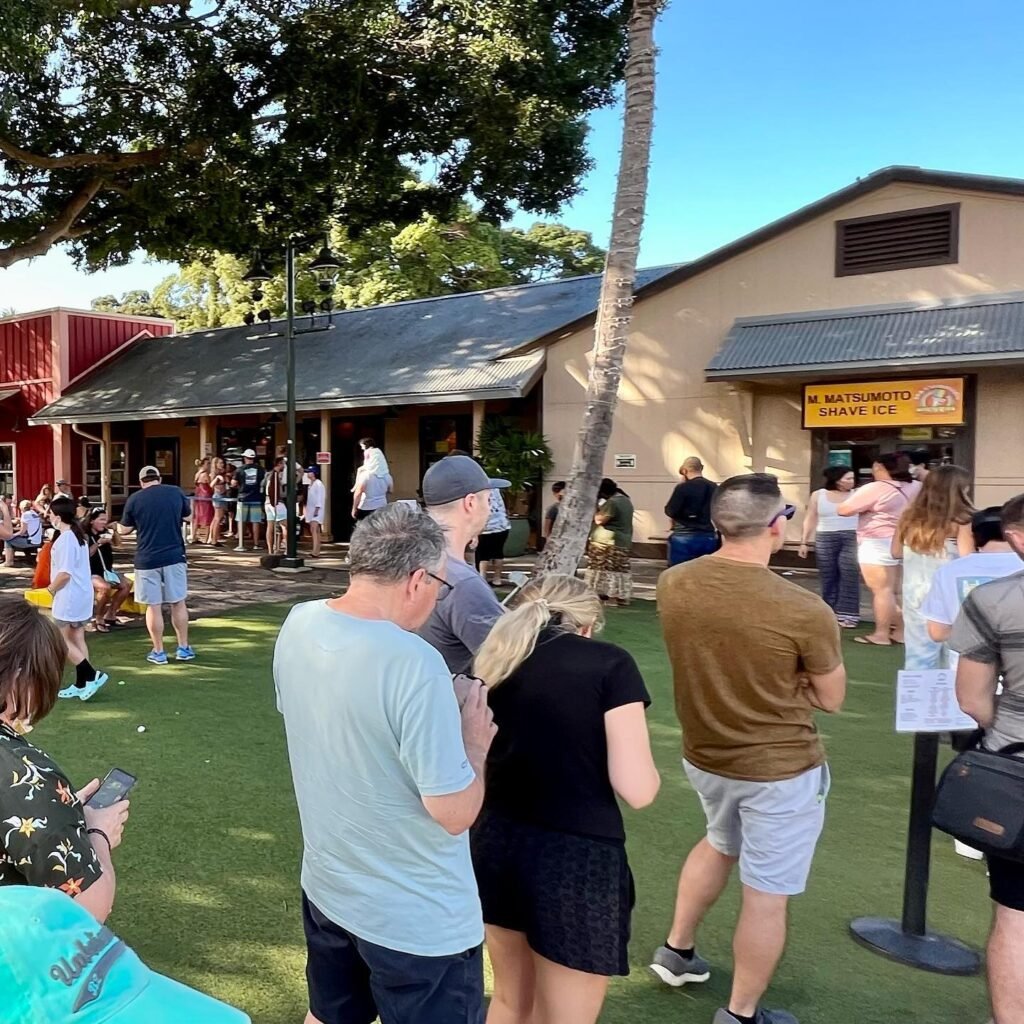 A group of people gathered on a lawn outside a zoo building under a clear blue sky.