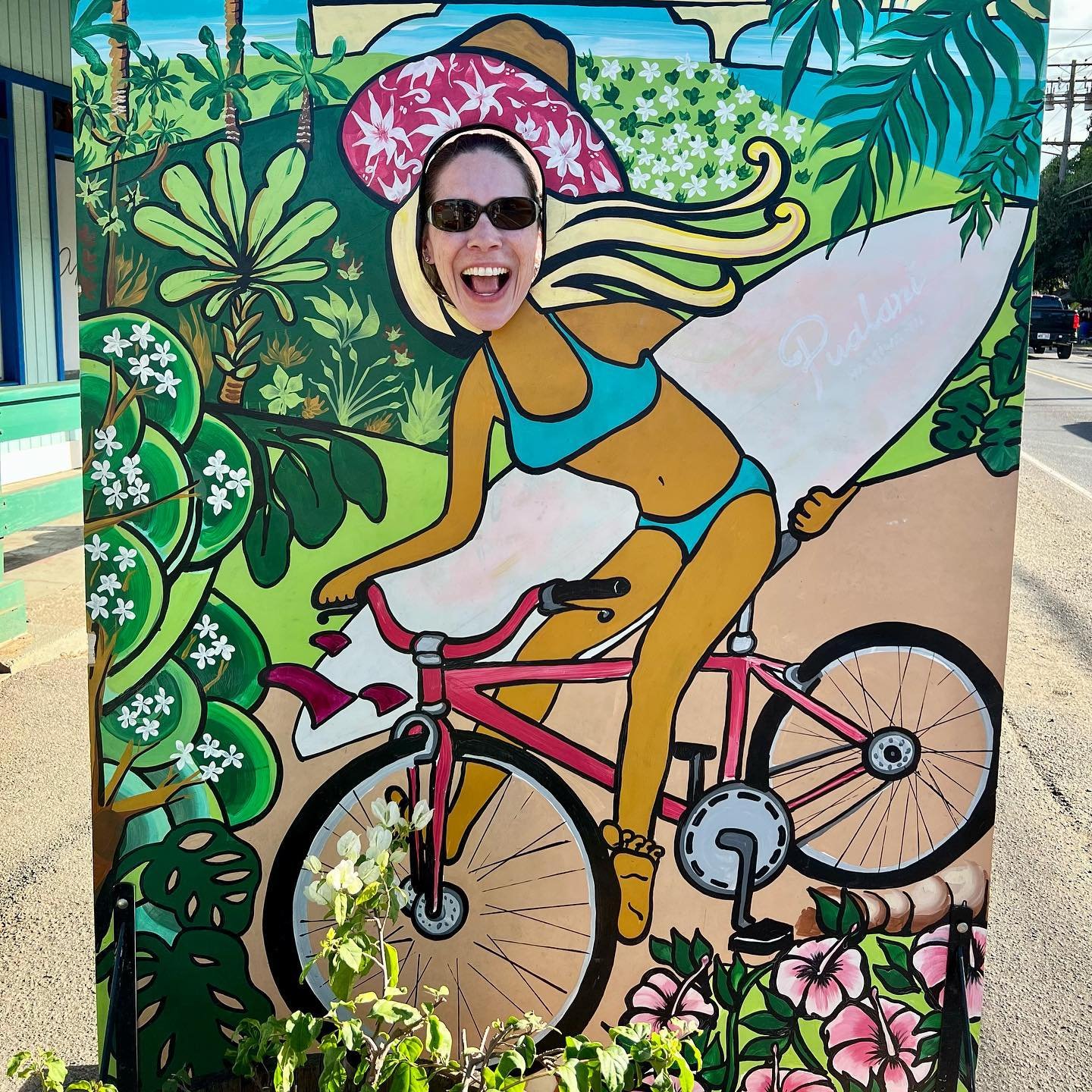 Haleiwa A colorful face board depicts a cyclist surfing through a tropical landscape.