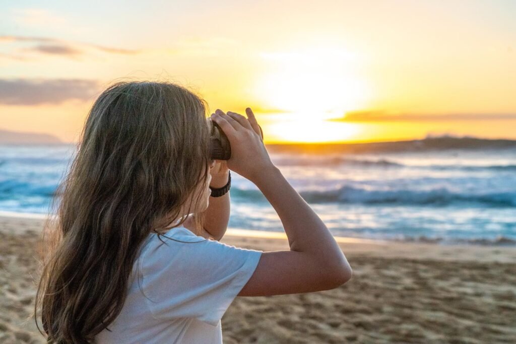 A person observing a beautiful sunset over the ocean from a sandy beach.