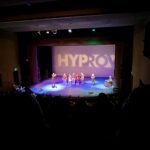 Sunset Beach (Oahu) View of a HYPROX live performance on stage. The scene is captured from the audience perspective.