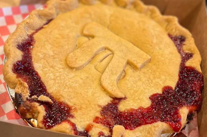 Two photos of a rustic cherry pie in a cardboard box lined with red checkered paper, featuring a golden crust with a decorative cut-in design.