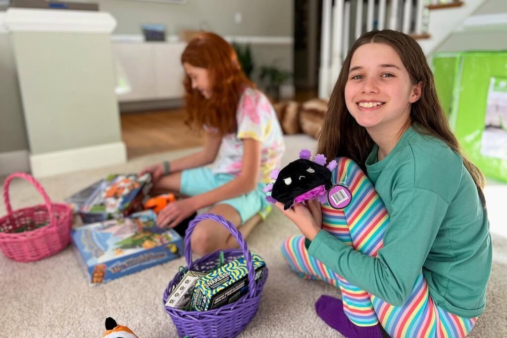 Family members sitting on the floor with colorful Easter baskets and toys in a bright living room.