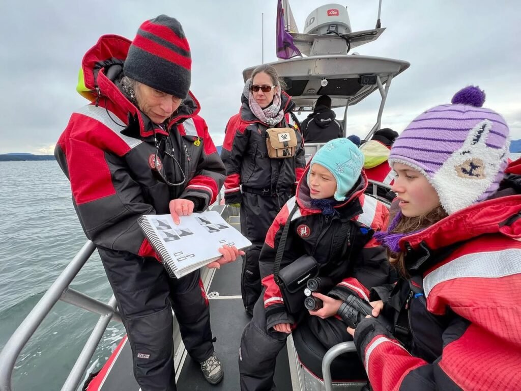 A family dressed in cold-weather gear reviewing a map on a boat near the water.