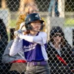 Orca Watching A baseball player prepares to bat while spectators watch from behind a chain-link fence.