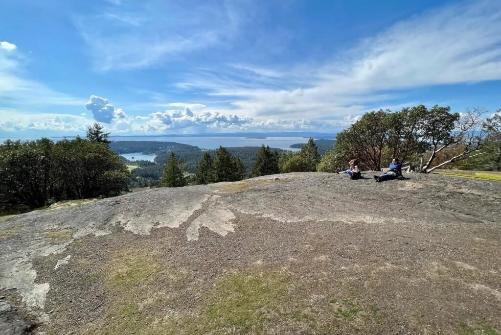 Wide panoramic view of a vast coastline and blue ocean from a high rocky outcrop.