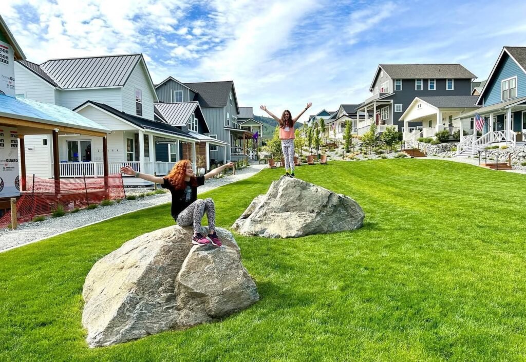 People enjoying a sunny day at the Moss Landing waterfront. Visitors playing on decorative rocks in front of scenic cottage-style homes.