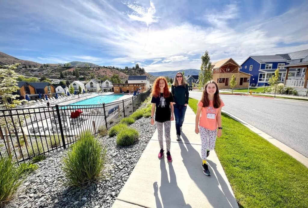 A group of people walking on a sunny day near a swimming pool and residential buildings.