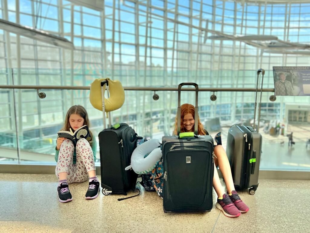 A group relaxing and reading at an airport terminal while surrounded by their travel luggage.