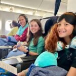 A family enjoys their flight with headsets and travel pillows.