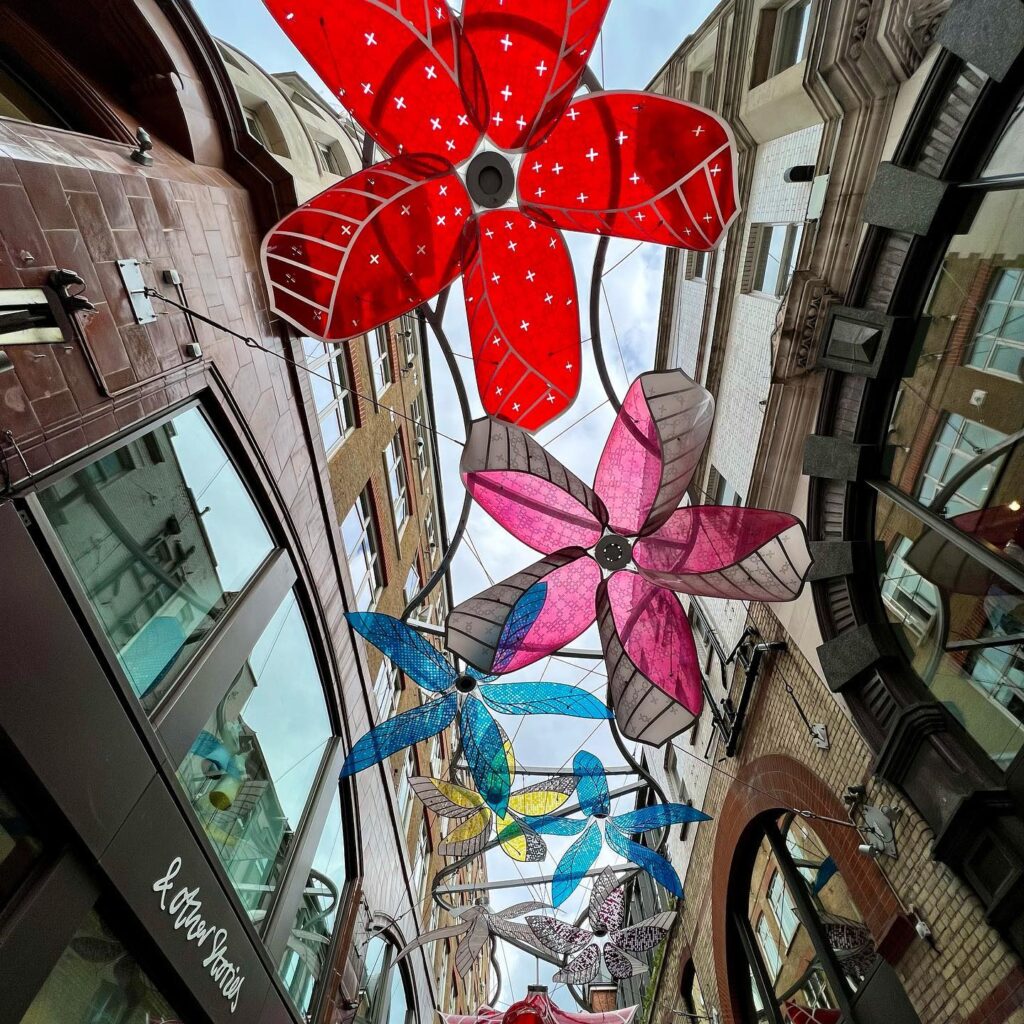 Vibrant, flower-shaped lanterns hanging across a city street, adding festive color to the urban landscape.