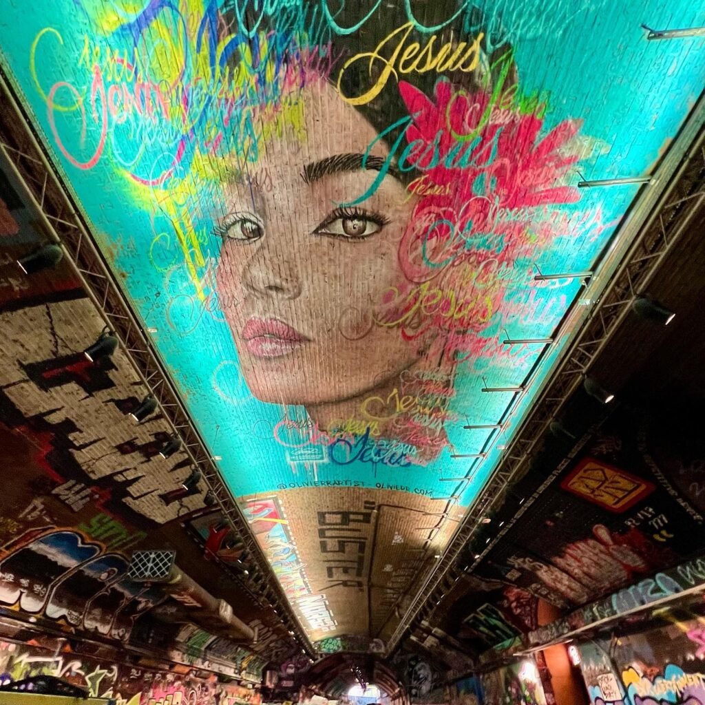 Colorful ceiling mural featuring a face and floral elements with vivid splashes of color.