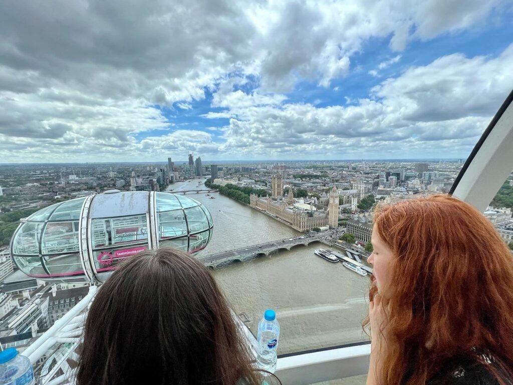 Looking out from the London Eye capsule toward the city skyline and the River Thames under a partly cloudy sky.