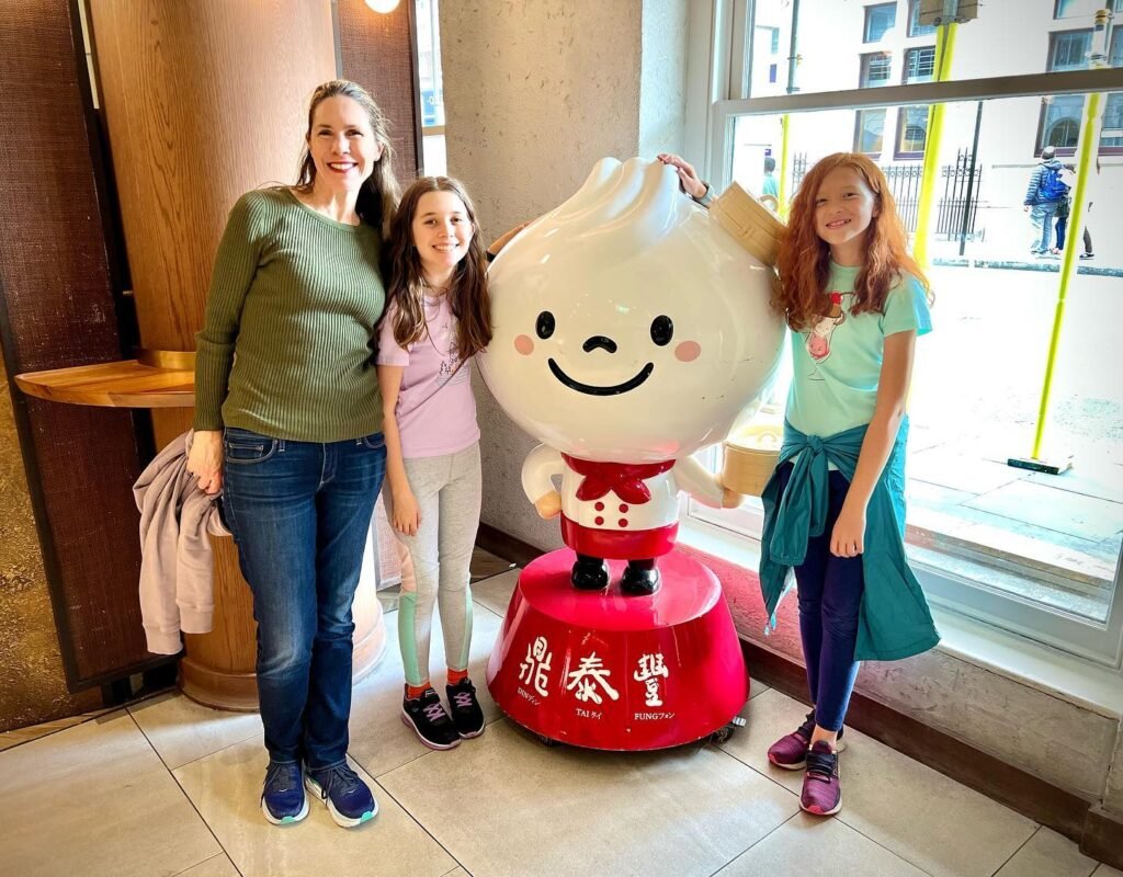 A smiling family poses with a large, cartoonish dumpling mascot in a Japanese restaurant setting.