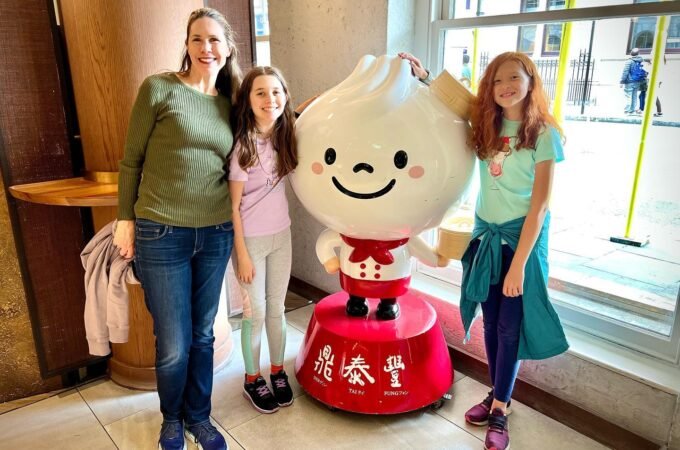 A smiling family poses with a large, cartoonish dumpling mascot in a Japanese restaurant setting.