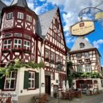 Feuchtwangen A collage of picturesque half-timbered houses with red and white facades and a traditional German-style hanging sign under a blue sky.