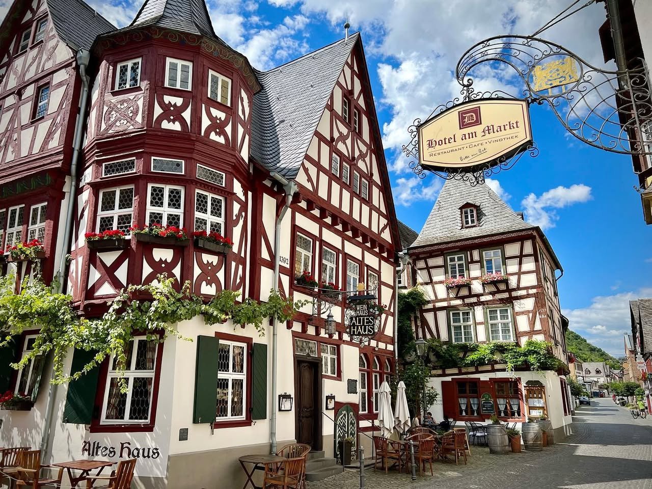 Bacharach A collage of picturesque half-timbered houses with red and white facades and a traditional German-style hanging sign under a blue sky.