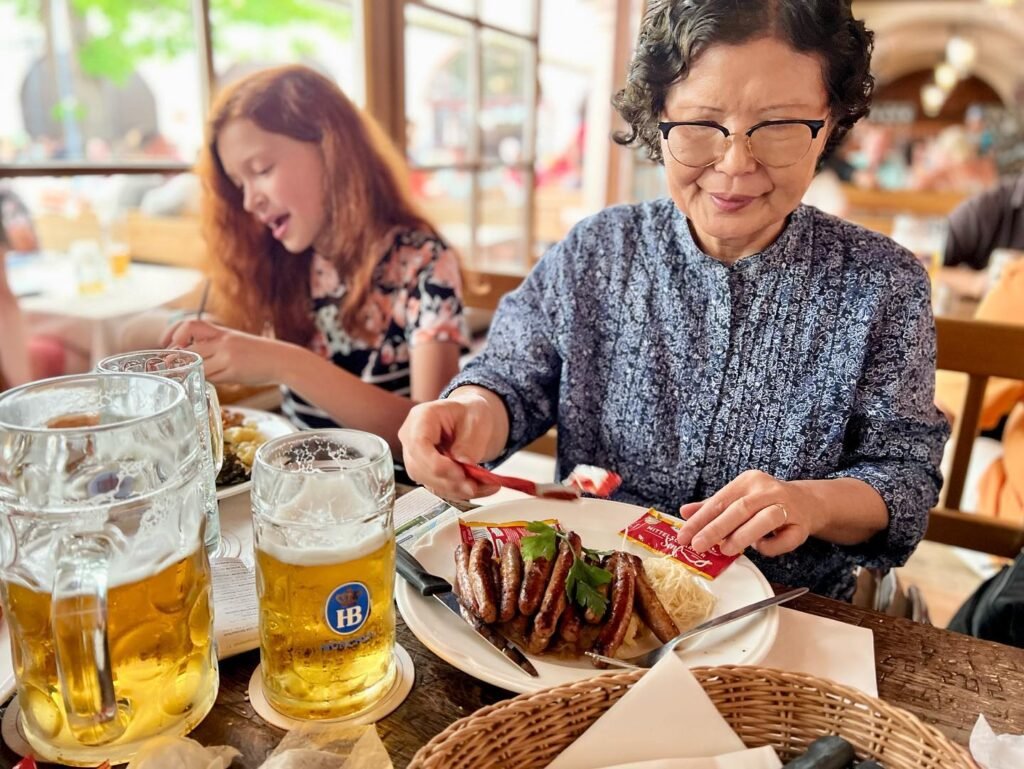 People enjoying a lunch of pretzels, cured meats, and beer in a bright, airy restaurant setting.