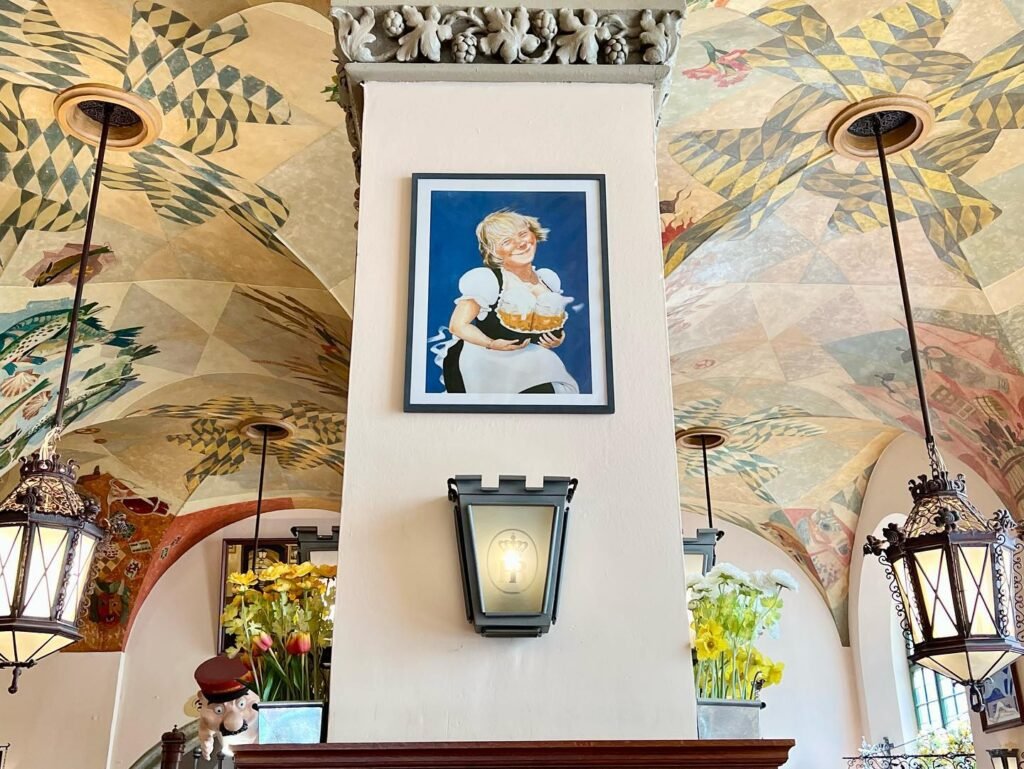 Intricate painted wooden ceilings with floral patterns above vintage-style lanterns and decorative wall sconces.