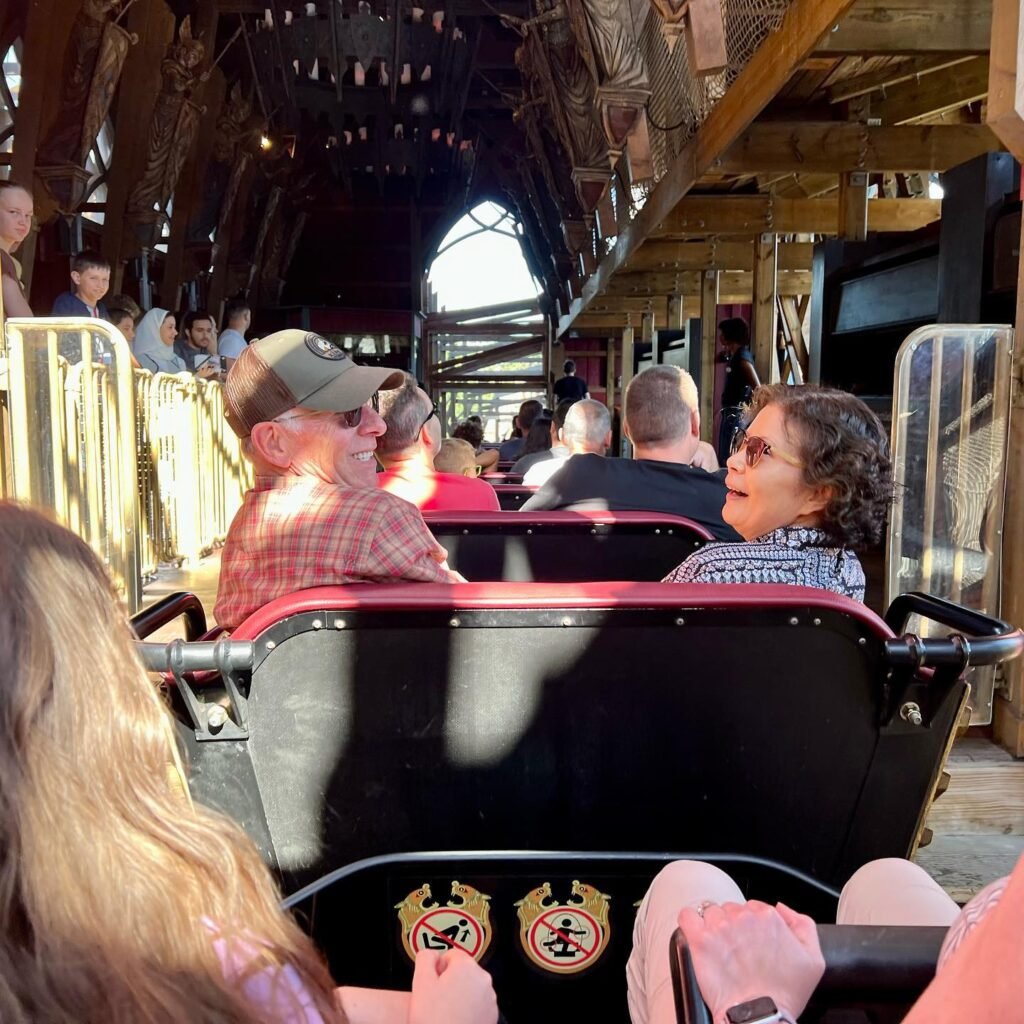 Riders enjoying a ride on the classic Excelsior roller coaster with its ornate wooden structure.