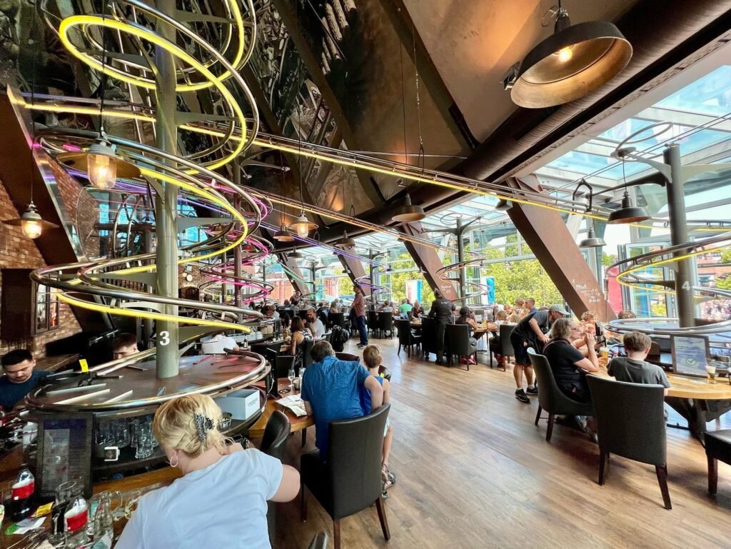 A cozy café interior featuring wooden floors, large windows, and striking spiral light installations.